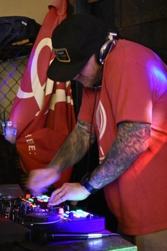 DJ Ravick mixing on his controller under colorful event lighting